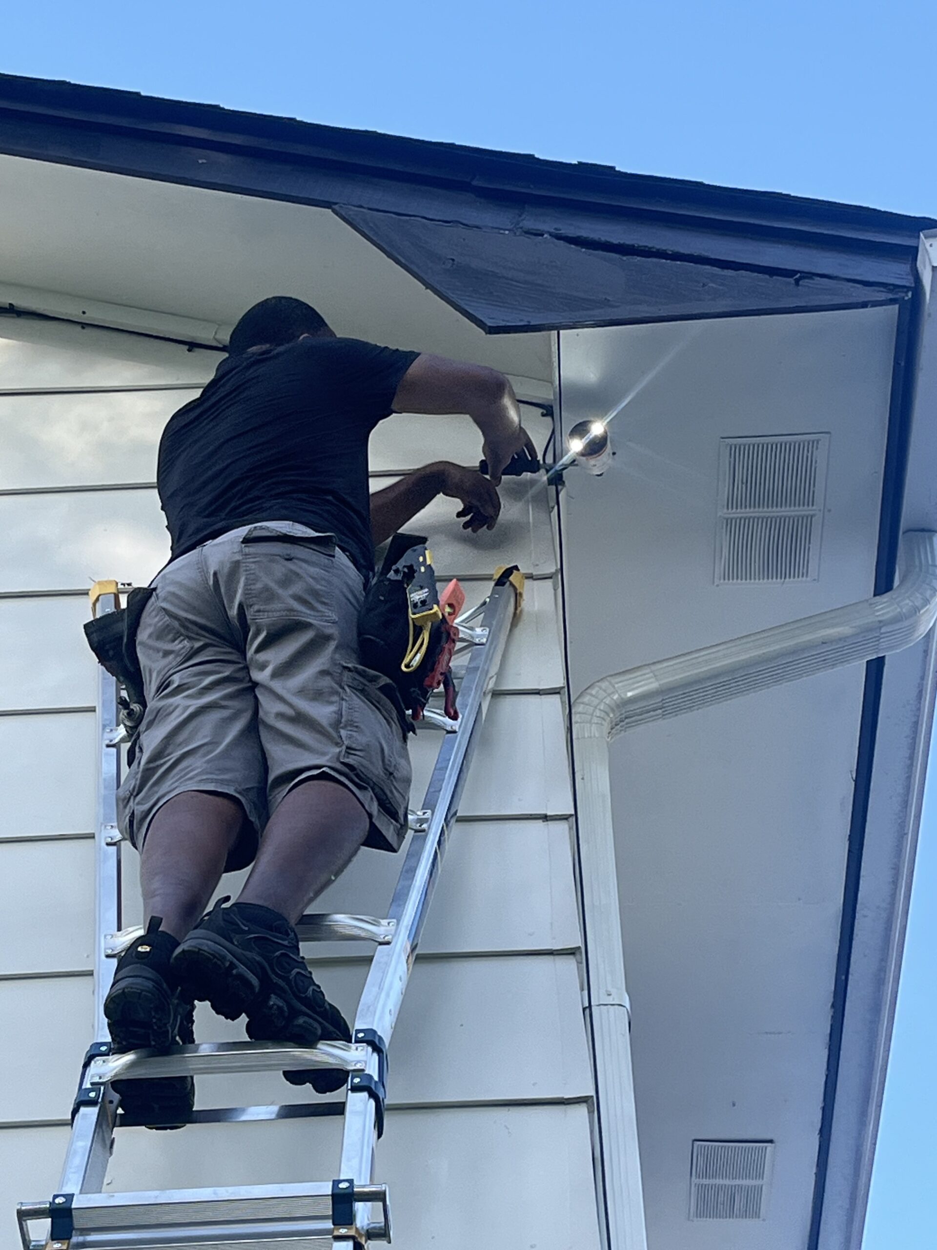 Technician fitting a camera under a roofline