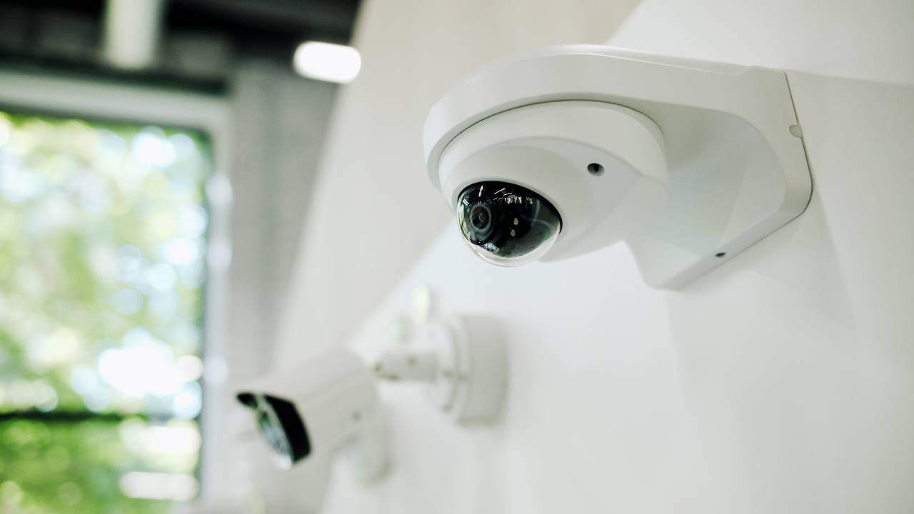 Dome and bullet cameras mounted on an interior wall beside a window